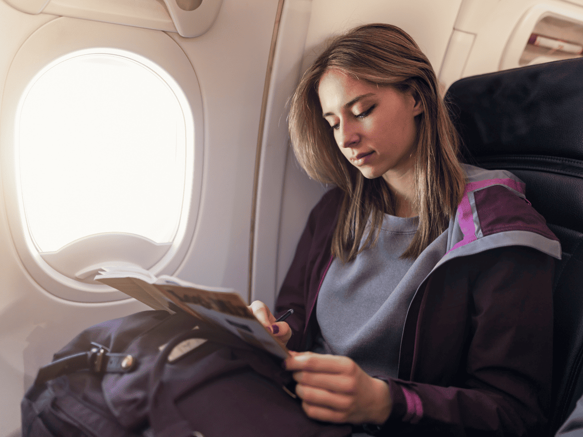 teen reading book on plane